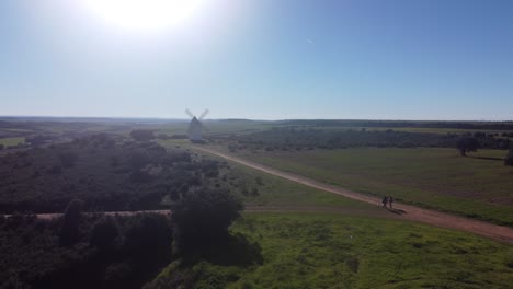 two people walking a dog towards ancient medieval windmill