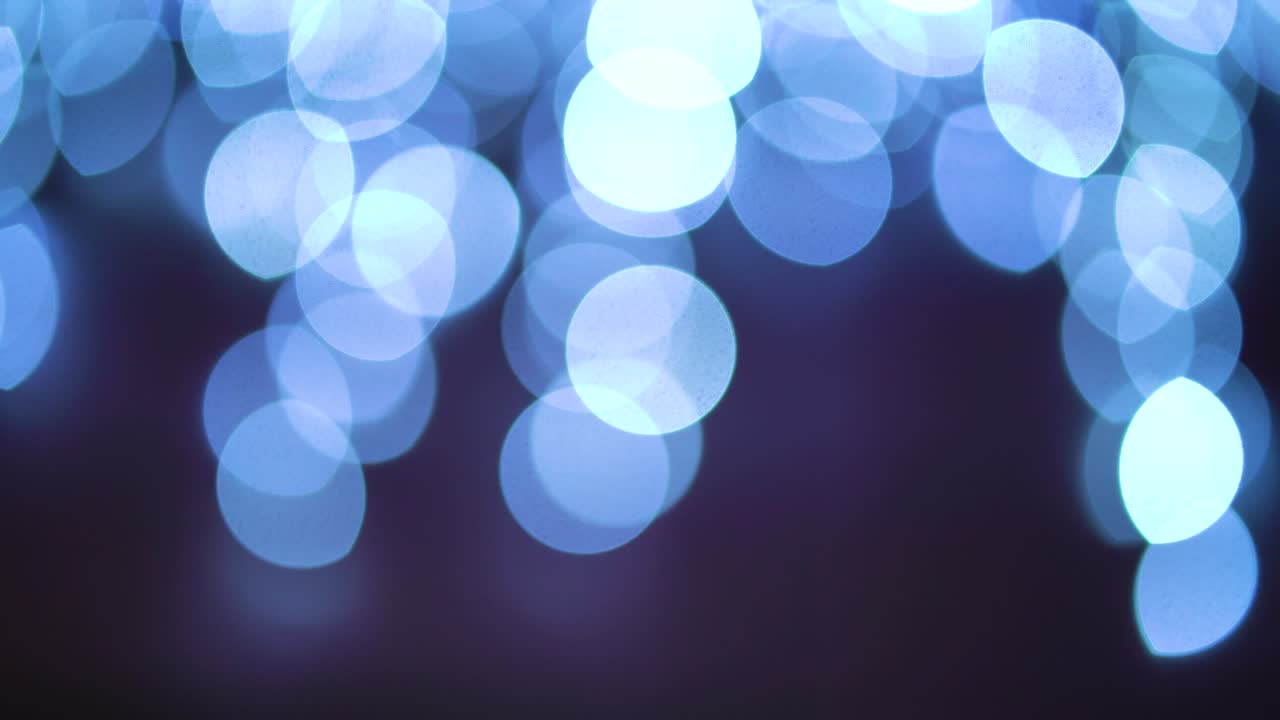 círculos de luz azul bokeh que se agitan sobre un fondo negro