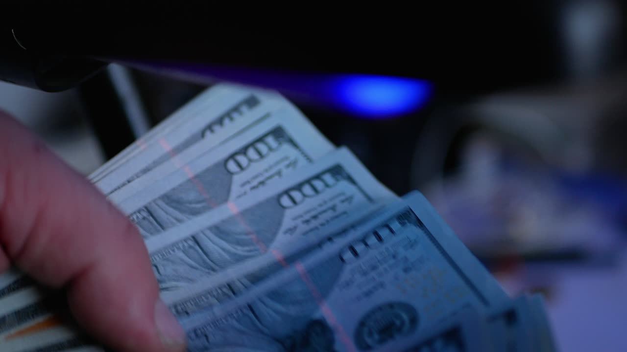 billetes de dólar en el detector de dinero en la oficina de cambio