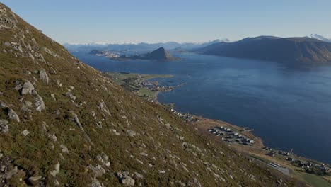 Toma-Aérea-Inclinada-Hacia-Arriba-De-Un-Grupo-De-Excursionistas-En-Una-Montaña-Rocosa-En-Noruega-Con-Un-Fiordo-En-El-Valle