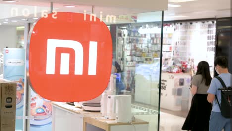people walk past a xiaomi flagship store with the logo of the chinese multinational technology and electronics brand at a shopping mall in hong kong, china.