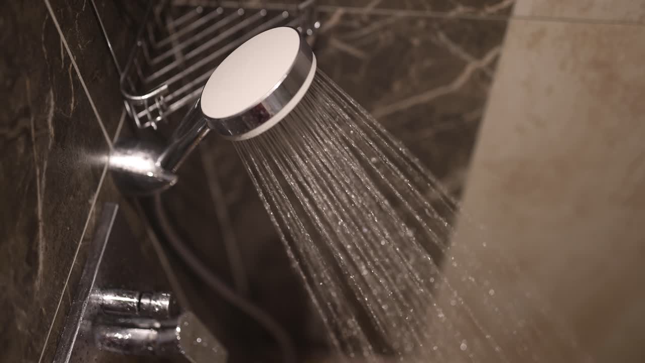 Water spraying from a modern shower head in a bathroom