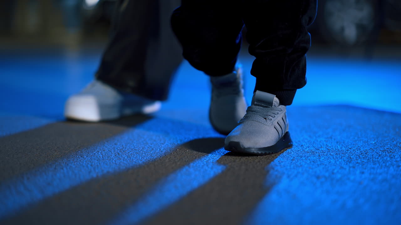 Unrecognized baby boy wearing grey sneakers making little steps. Close up. Small kid learning to walk.