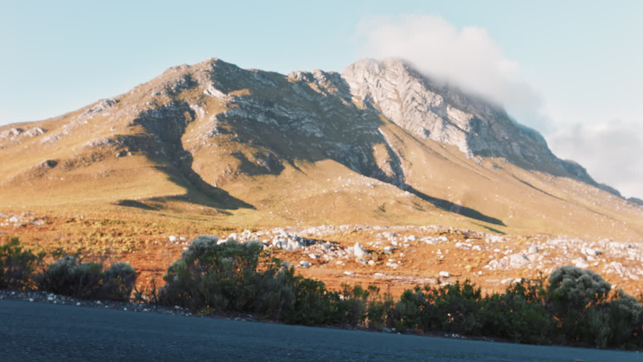 젊은 여성 스케이팅 선수가 롱보드 타고 내리막길을 타고 해가 지는 아름다운 시골 도로에서 빠른 스케이팅을 하며 여름 휴가를 즐기고 있습니다. 아름다운 풍경 배경