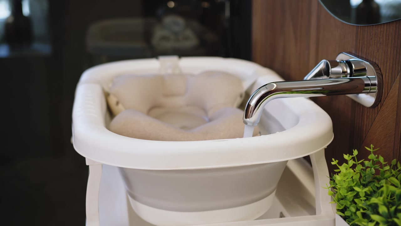 Parent prepares babys bath by gathering towels toys and checking water temperature for safety and