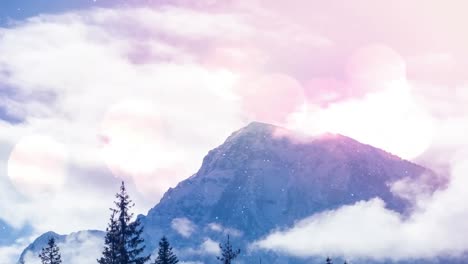 spots of light and snow falling over multiple trees and mountain on winter landscape