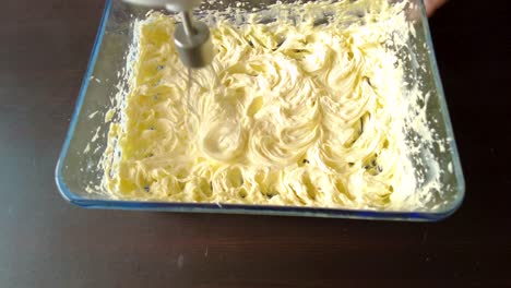 latin woman wearing an apron preparing cooking baking a cake mixing the butter with a mixer