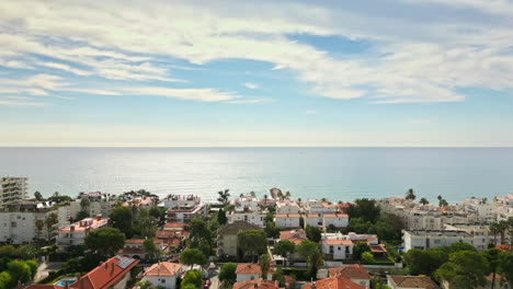 Drohnenaufnahmen-Erfassen-Malerische-Ausblicke-Auf-Küstenhäuser-Am-Strand-Und-Bieten-An-Einem-Sonnigen-Tag-Atemberaubende-Ausblicke-Auf-Das-Weite-Meer