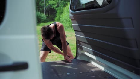 man tightening screw on the floor inside a van