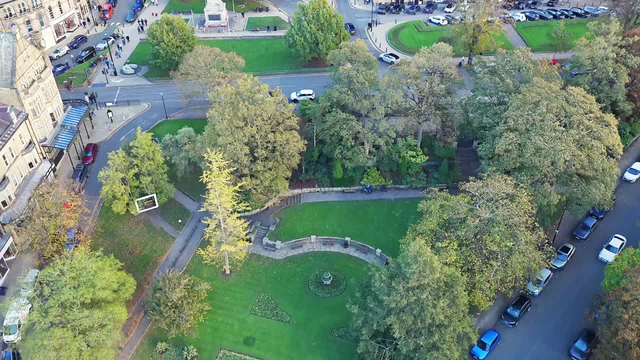 Aerial above Prospect Square, Harrogate, reveals a semicircular stone wall, gardens, autumn trees, and classic parkland at the centre of the town