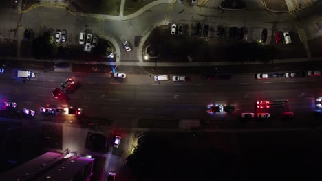 top-down aerial footage captures emergency services intervening on a blocked highway during nighttime, highlighting their quick response and teamwork