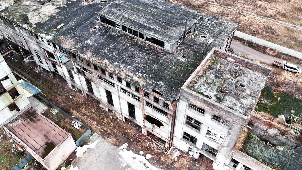Large buildings of an old abandoned factory not used for a very long time. Forlorn empty premises with no windows or parts of the walls. Aerial view.