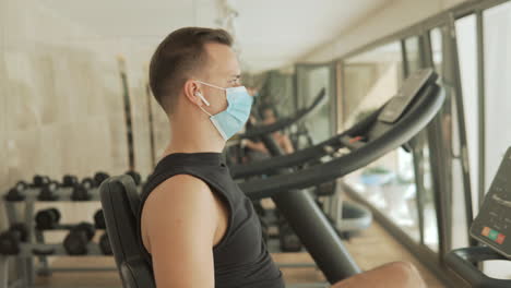 young strong athlete male man with face mask looking to camera in the gym