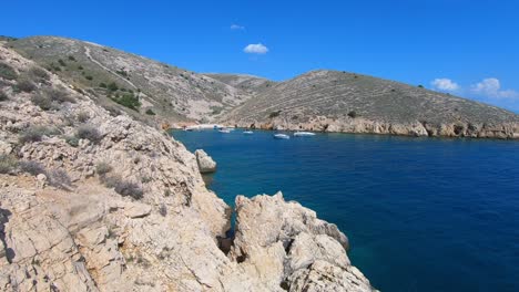 Moonlike-shores-of-Krk-Island-and-motorboats-at-beautiful-blue-bay