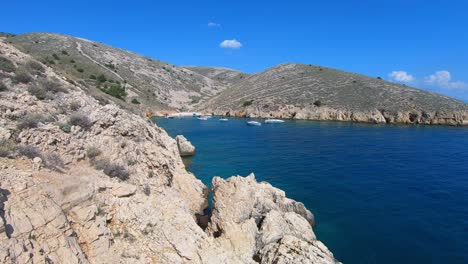 mondähnliche ufer der insel krk und motorboote in der wunderschönen blauen bucht