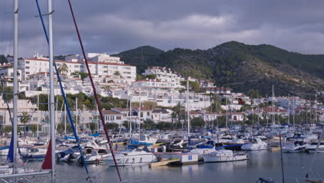 Lapso-De-Tiempo-De-Barcos-Atracados-En-Un-Puerto-Estacionado-Junto-A-Un-Pueblo-Montañoso,-Mientras-La-Luz-Del-Sol-Ilumina-El-Paisaje-Circundante