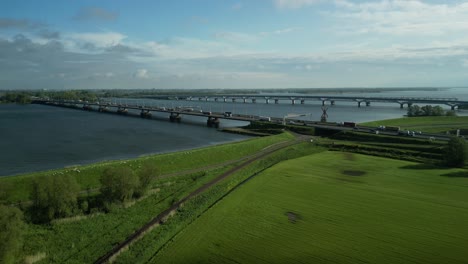 Observando-El-Tráfico-Sobre-El-Puente-De-Moerdijk-Con-Un-Dron-Flotando-Sobre-Un-Paisaje-De-Pólder-Holandés.