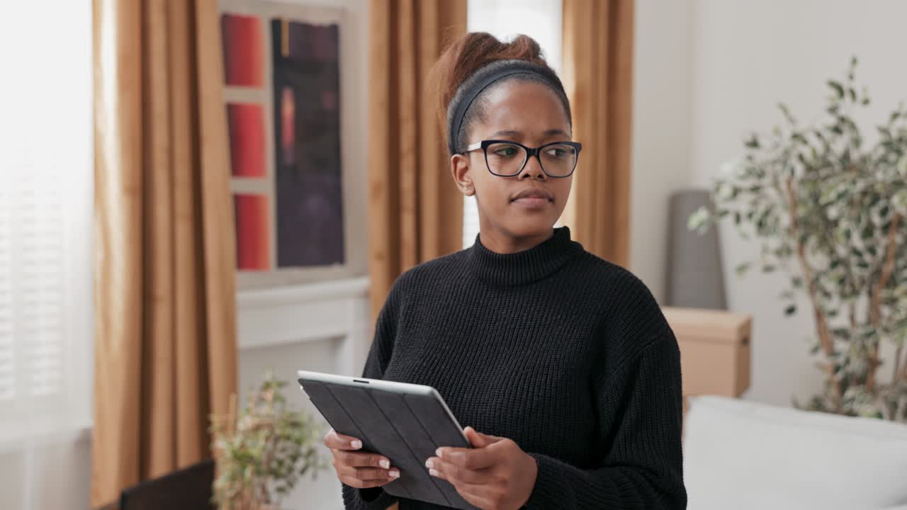 Smiling attractive girl orders furniture online for new apartment, decorates home after move, looks for decorating inspiration, evaluates how it will look in her home, uses tablet