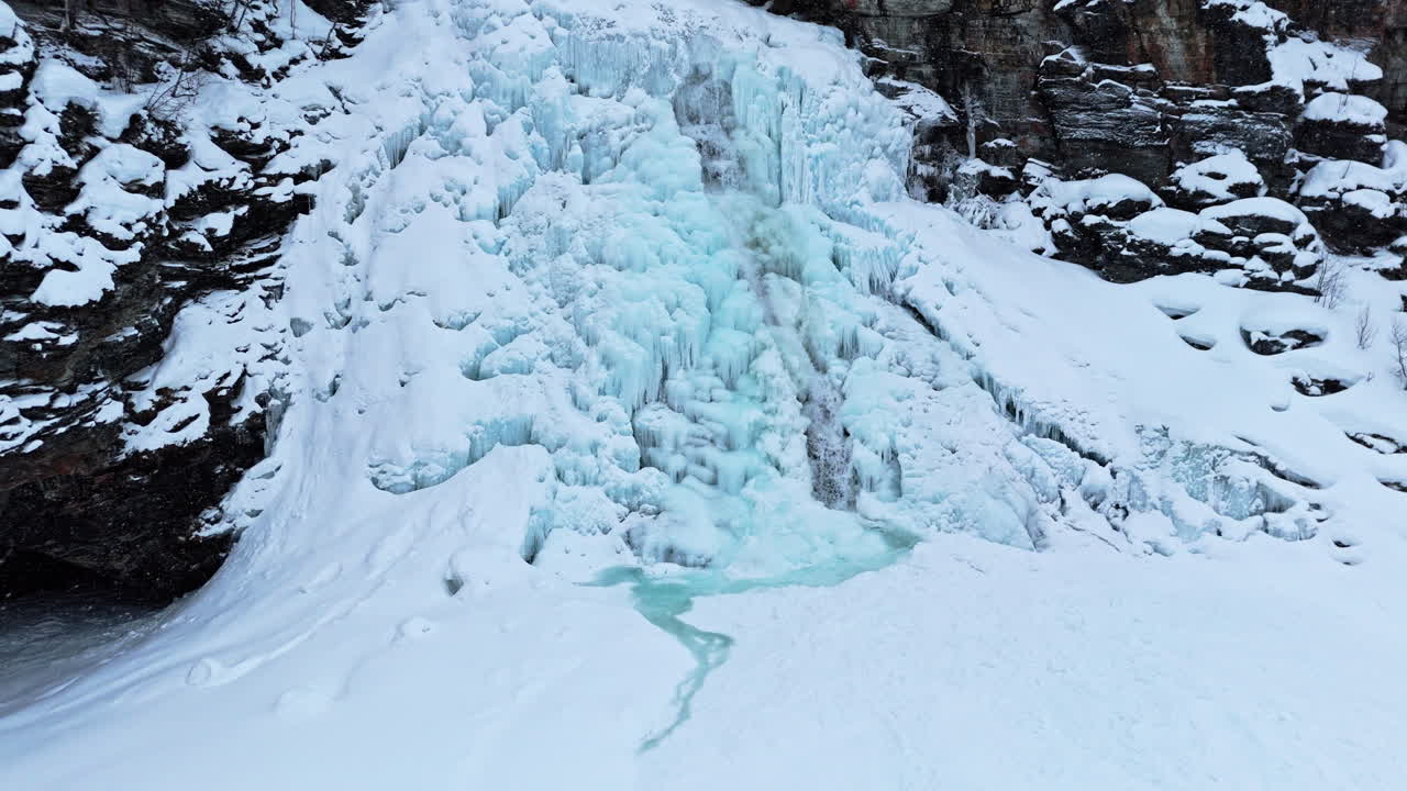 Frozen waterfall in Norway near Rovijoen Putous, icy blue cascades in a winter landscape