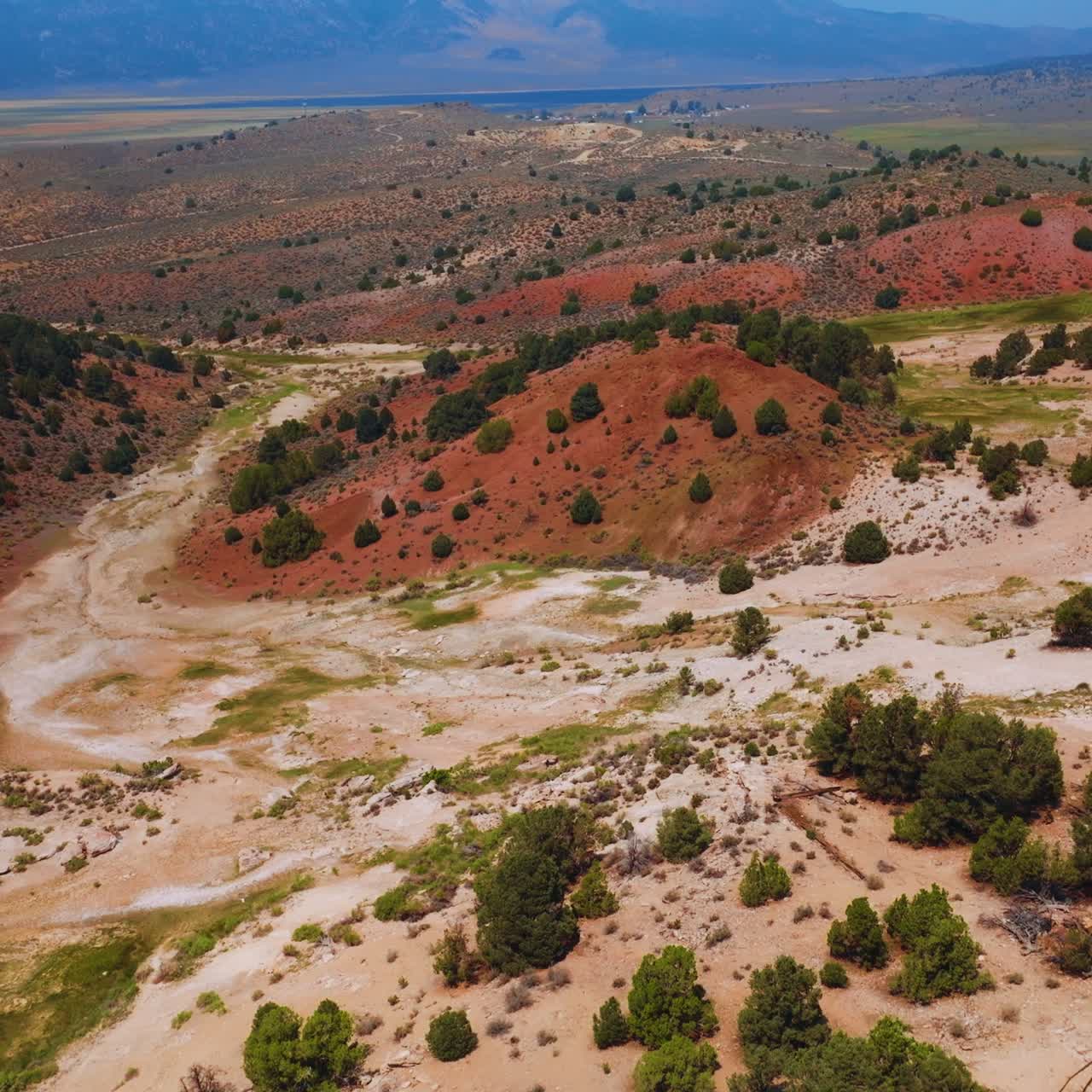 Travertine rough uneven landscape with brown hills and light ground between them. Hazy blue mountainous horizon at backdrop