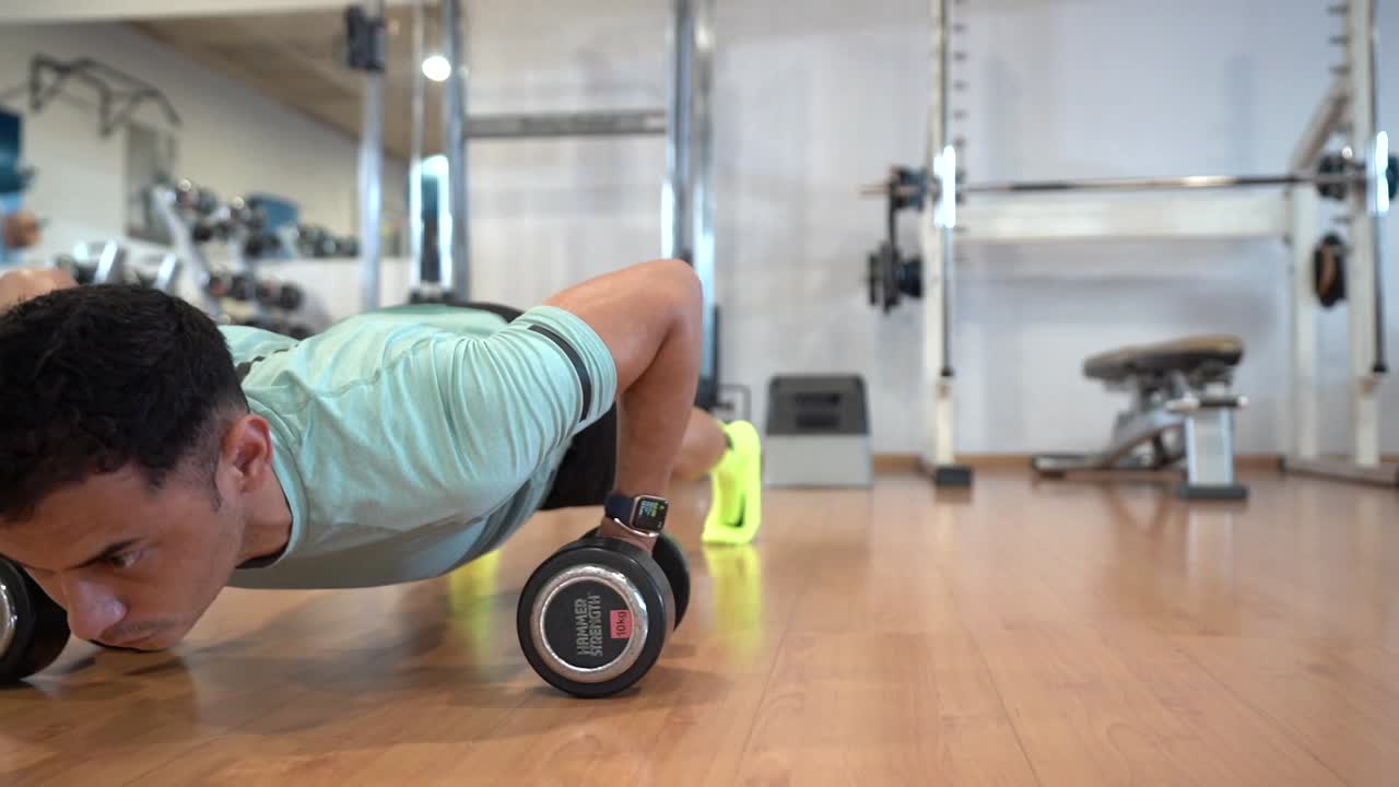 Man doing push-ups with dumbbells in a gym