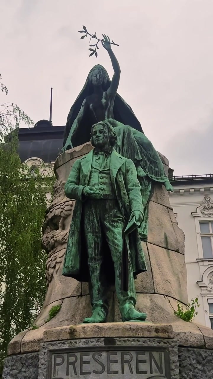 Primo piano verticale del Monumento a France Prešeren a Lubiana, che mostra la statua in bronzo del poeta e la musa allegorica che tiene un ramo d'alloro sopra il piedistallo in pietra.