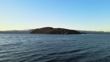 Bird's-eye-view-flying-close-to-the-agitated-Nahuel-Huapi-lake,-towards-the-boscow-island-on-a-blue-sky-day