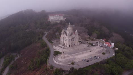 Wide-shot-of-Santuário-de-Santa-Luzia-Portugal-during-a-moody-day-low-clouds,-aerial