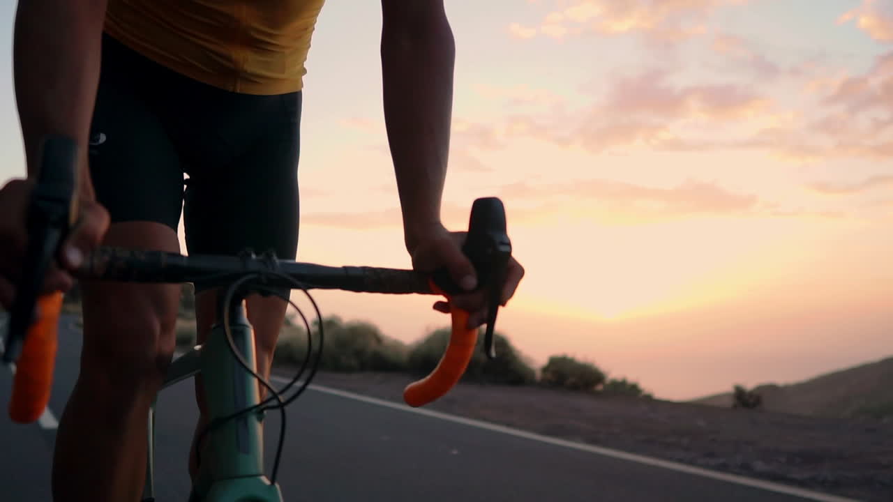 The athlete on a bike navigates a mountain serpentine in slow motion, enjoying the island's view, embodying dedication to a healthy lifestyle at sunset
