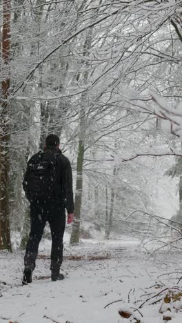 man walking through snowy forest