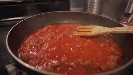 salsa de pasta roja burbujeando en cámara lenta sobre el fuego en una estufa de cocina
