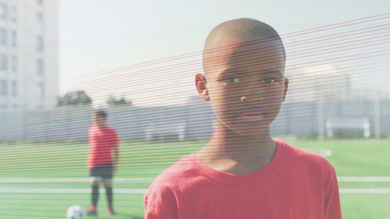 Camera moving in, boy holding gaze, team dribbling ball, scanline flashing over boy in youth sports