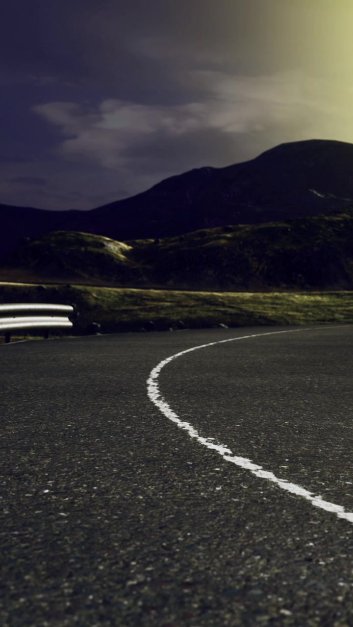 Curved road with mountain backdrop during nighttime