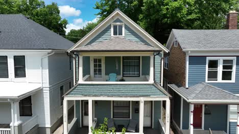 classic blue american house with a front porch and gabled roof, nestled between similar homes