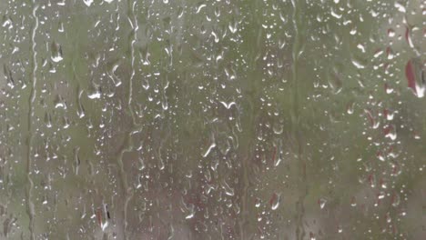 rain streaks and water droplets on window with blurry green background