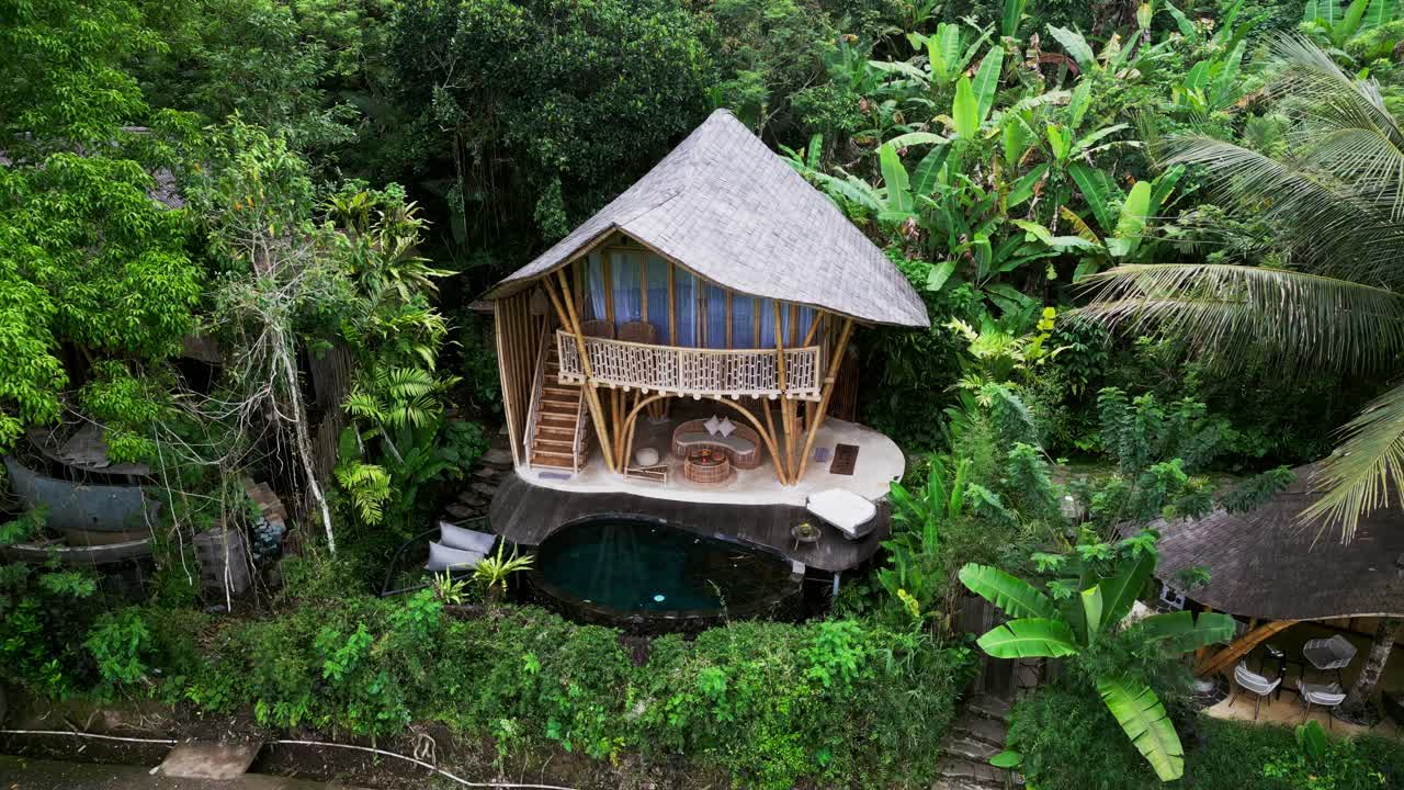 Aerial shot of an eco bamboo villa in Bali’s tropical forest near Sidemen, surrounded by palm trees and greenery, highlighting sustainable design and nature inspired architecture with relaxing vibes