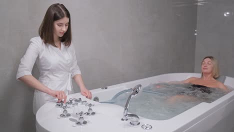 a woman enjoying a hydromassage in a jacuzzi. a relaxed woman receives a hydromassage from a professional beautician in a spa center.