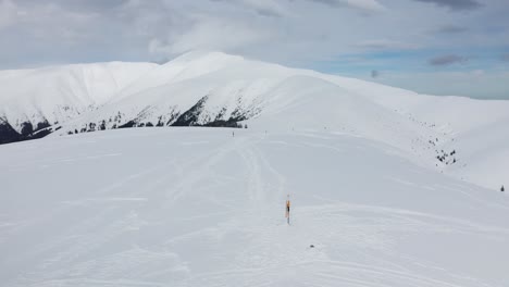 Snow-covered-slopes-with-skiers-at-Papusa-Peak,-Iezer-Papusa-Mountains,-Arges,-Romania,-wide-shot