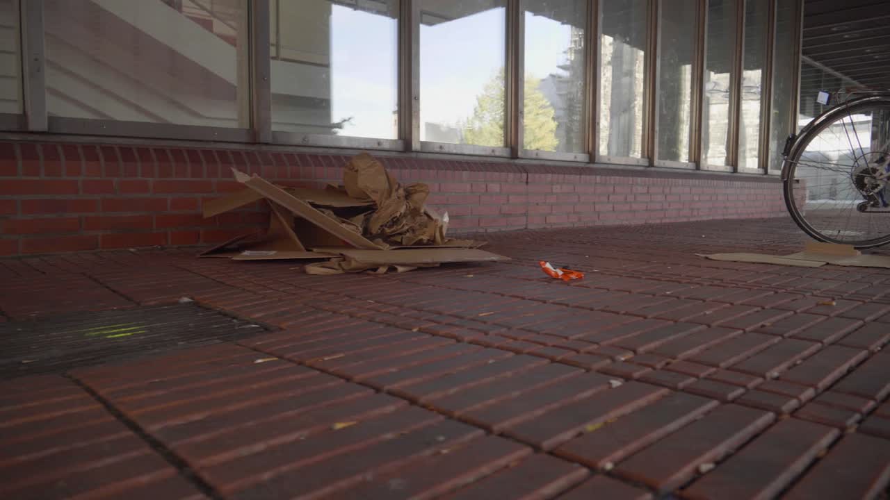 주차된 자전거 옆에 있는 도시의 거리에 있는 쓰레기와 먼 곳을 걷는 사람들의 핸드헬드 샷