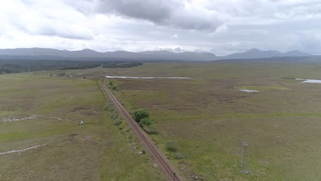 aerial push in shot of rannoch moor and the train line that sits in the landscape