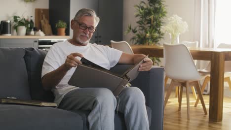 hombre caucásico mirando fotos viejas en el álbum en casa.