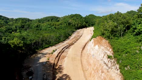 Vibrant-green-jungle-and-prepared-land-plot-for-road-construction,-aerial-view