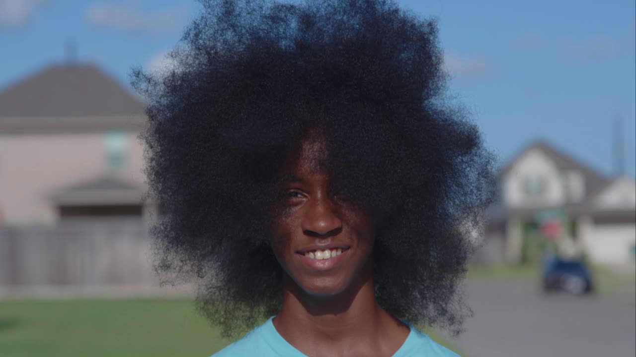 adolescente afroamericano con un enorme afro mirando a la cámara
