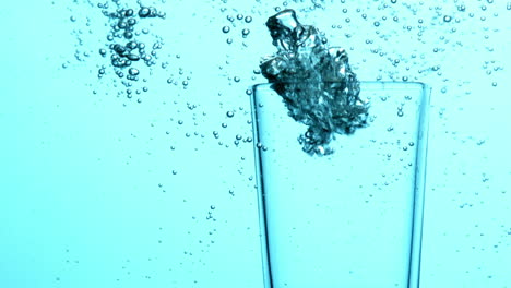 bubbles rising from glass submerged in blue water