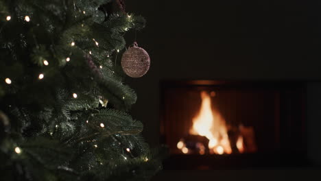 A-fire-burns-in-a-fireplace-in-a-dark-room.-Blurred-Christmas-tree-lights-in-the-foreground.-Christmas-Eve