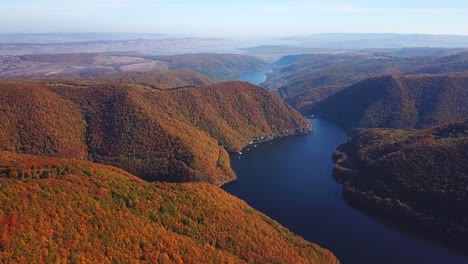 Aerial-view-over-lake-Tarnita,-Romania,-surrounded-by-colorful-autumn-trees