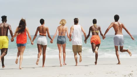 Group-of-mixed-race-friends-running-together-hand-in-hand-on-the-beach-4k