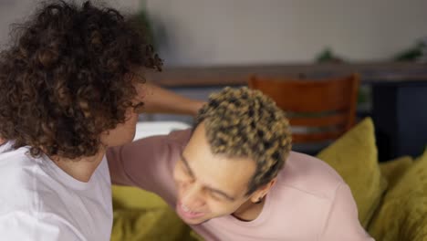 Young man making marriage proposal to his boyfriend, hugging together on a sofa in living room