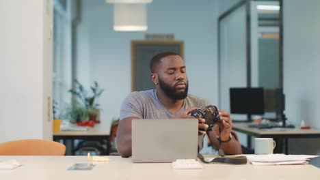 african man connecting camera to notebook. man recording photos to computer