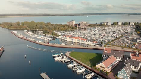 Vista-Aérea-De-Drones-Del-Puerto-De-Huizen-Mostrando-Los-Alrededores-Más-Amplios-Con-El-Lago-Gooimeer-Y-Flevoland-En-El-Fondo-Con-Molinos-De-Viento